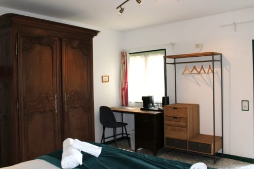 Comfortable double room at Domaine des Piéris with wooden wardrobe, desk, clothing rack, and garden view window