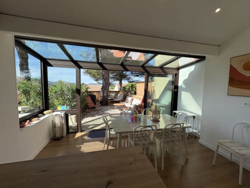 Espace repas de la villa moderne Mazet Cavalaire avec pergola vitrée, vue sur mer et terrasse extérieure à Cavalaire-sur-Mer