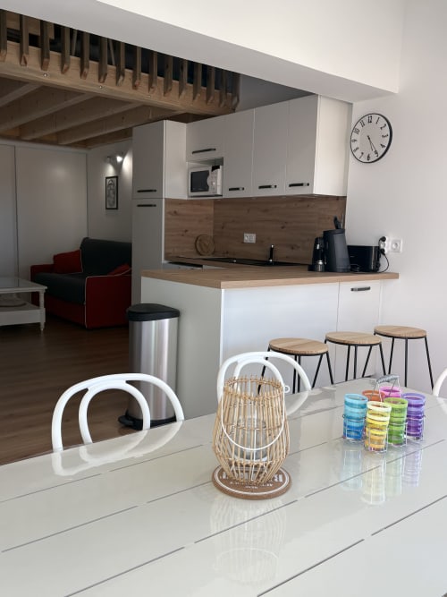 Cuisine ouverte et salle à manger modernes à Mazet Cavalaire avec armoires blanches, accents en bois et coin bar
