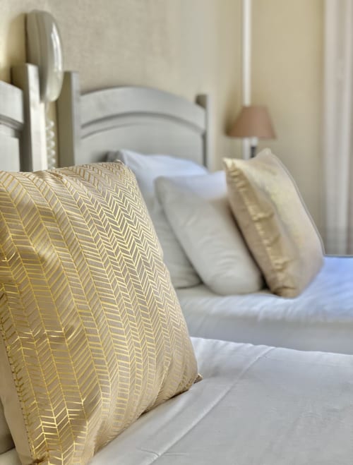 Cozy bedroom at Hôtel Maison Richet with yellow patterned pillow, white bedding, and coastal ambiance in Les Sables-d'Olonne