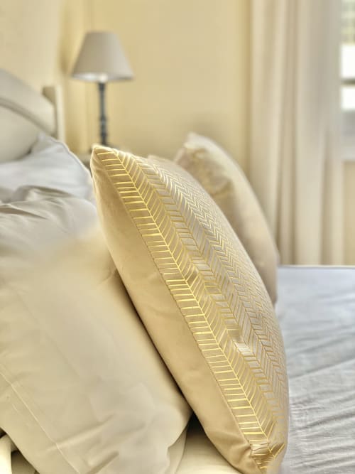 Cream and gold decorative pillows on a bed at Hôtel Maison Richet, a family cottage in Les Sables-d'Olonne
