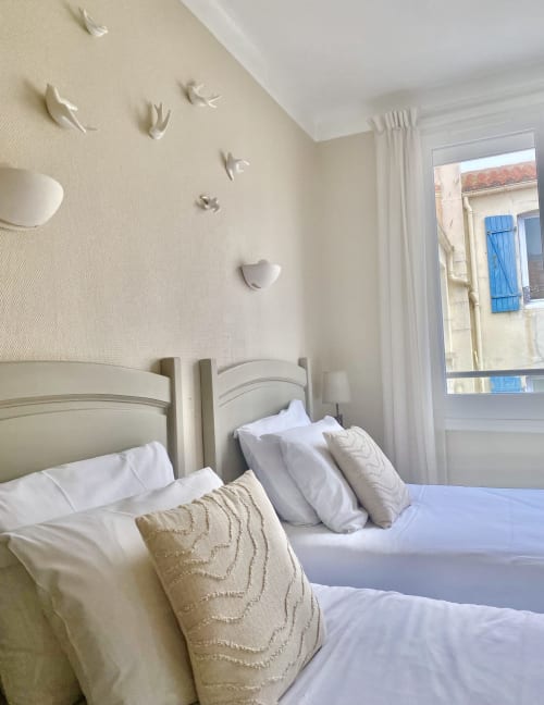 Serene bedroom at Hôtel Maison Richet, Les Sables-d'Olonne, with twin beds, white linens, and coastal decor near window