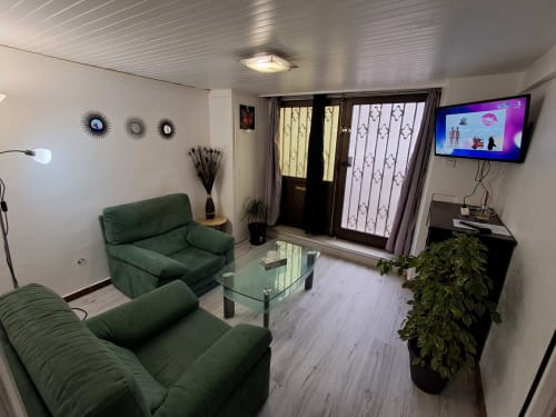 Salon moderne de la chambre B de NancyRoom à Vandoeuvre-les-Nancy avec canapé vert, téléviseur écran plat et vue sur la ville