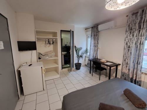 Chambre double moderne à NancyRoom B&B à Vandoeuvre-les-Nancy avec TV, bureau, salle de bain et vue sur la ville depuis le balcon