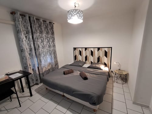 Chambre double moderne au NancyRoom B&B à Vandoeuvre-les-Nancy avec tête de lit géométrique, rideaux à motifs et style contemporain