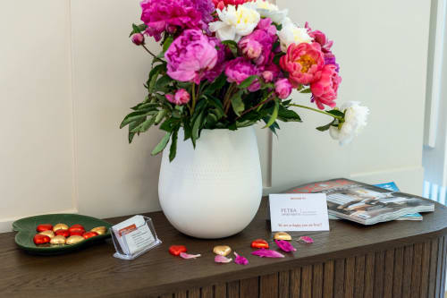 Benvenuto a Petra Apartments Rome con peonie rosa in vaso bianco su consolle in legno scuro