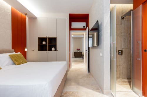 Camera da letto moderna agli Appartamenti Petra Roma con dettagli arancioni, bagno ensuite, letto con contenitori e arredi contemporanei