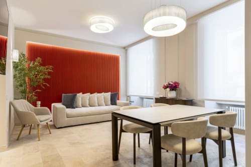 Zona living e dining moderna presso Petra Apartments a Roma con divano beige, parete rossa e arredi contemporanei