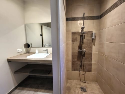 Modern bathroom at Villas Lantana with vanity sink, mirror, and walk-in shower with black tile accents