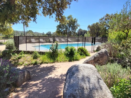 Pool at Villas Lantana in Lecci with safety fence, lounge chairs, and surrounding gardens under clear sky