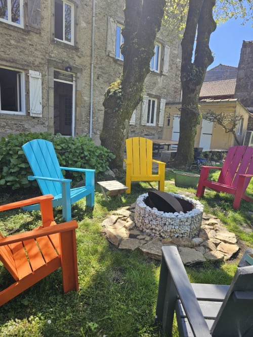 Chaises Adirondack colorées autour d'un foyer dans le jardin de la Bastide du Thoré, Labastide-Rouairoux