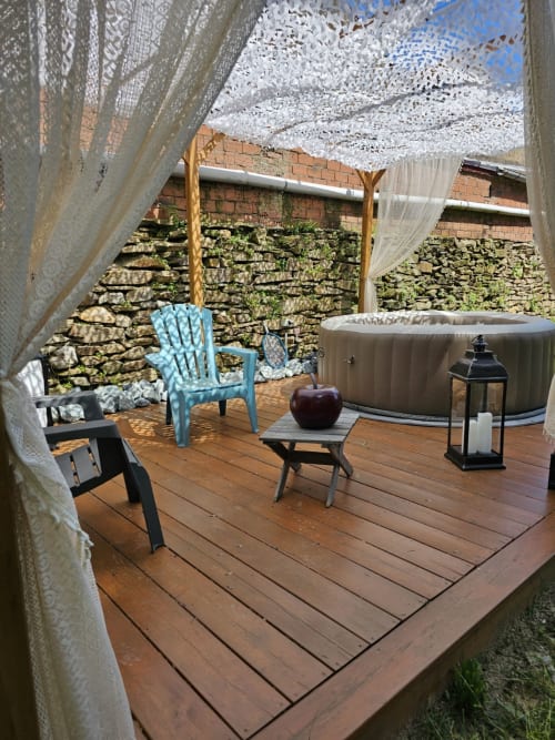 Terrasse spa extérieure à Bastide du Thoré avec bain à remous, chaises bleues et voile blanche à Labastide-Rouairoux