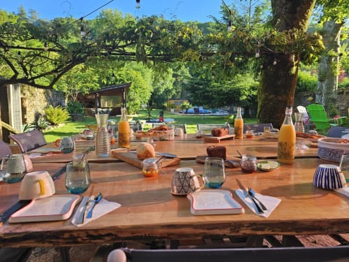 Table de salle à manger extérieure à la Bastide du Thoré à Labastide-Rouairoux avec couverts, boissons et vue sur le jardin luxuriant