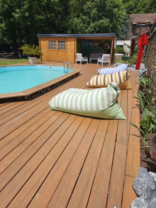 Terrasse piscine de la Bastide du Thoré avec transats rayés, terrasse en bois, piscine et pavillon de jardin à Labastide-Rouairoux
