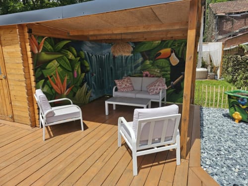 Espace lounge extérieur à Bastide du Thoré avec fresque tropicale, mobilier contemporain et pergola en bois à Labastide-Rouairoux