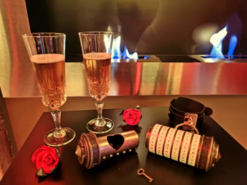 Dîner romantique avec flûtes à champagne, roses rouges et bijoux en forme de cœur à la chambre d'amour Les Secrets de Winna