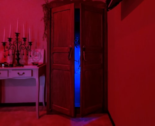 Red romantic bedroom with candelabra, wardrobe, and blue lighting at Les Secrets de Winna love room