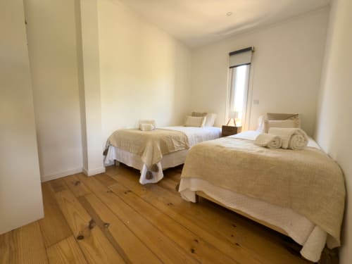 Twin bedroom with wooden floor and beige bedding at Corvatos Casas do Monte lake house villa in Almodôvar