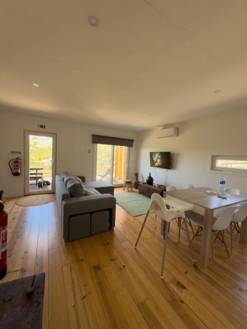 Modern Lake House villa living area with wood flooring, sofa, dining table, TV, and terrace access at Corvatos Casas do