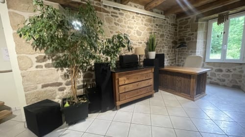 Intérieur de chaumière avec mobilier bois, plantes en pot et carrelage dans la retraite des Bois de Corrèze