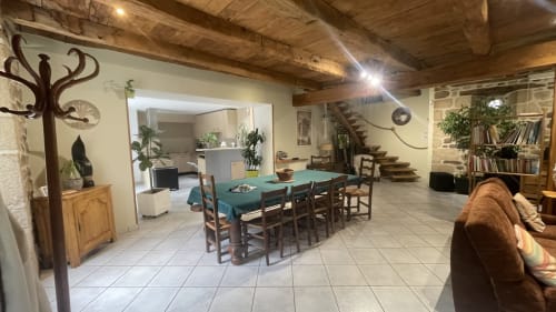 Spacieuse salle à manger familiale aux poutres en bois, table verte et mobilier rustique en Corrèze