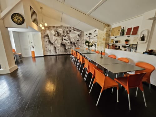 Moderner Essbereich des Gîte Le Manoir Lacustre mit orangefarbenen Stühlen, langem Tisch und künstlerischer Wanddekoration in Queyrac