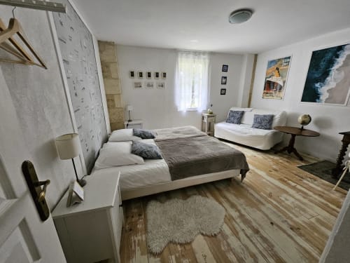 Geräumiges Schlafzimmer im Cottage Le Manoir Lacustre mit Doppelbett, Sofa, Holzboden und Gartenblick in Queyrac