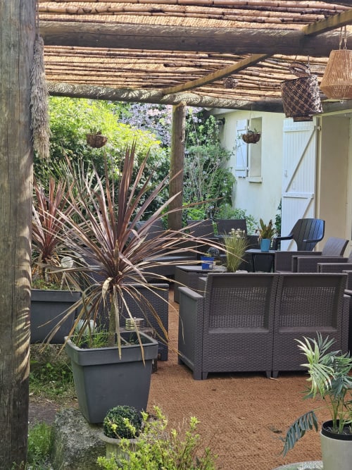 Schattige Pergola auf der Terrasse des Cottage Le Manoir Lacustre mit Rattanmöbeln, Topfpflanzen und Gartenblick in Queyrac