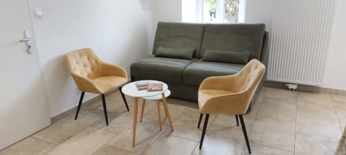 Séjour moderne du Gîte Bambou avec fauteuils ocre, canapé vert et table d'appoint blanche donnant sur le jardin