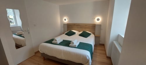 Chambre moderne du Gîte Bambou avec lit en bois, literie blanche, accents verts et éclairage ambiant à Alès, France
