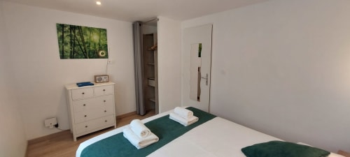 Chambre Gîte Bambou avec lit double, chemin de table vert, commode blanche et vue jardin au Mas de Trépeloup