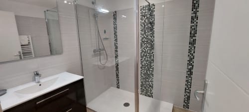Salle de bain moderne du Gîte Coquelicot au Mas de Trépeloup, Alès : douche carrelée blanche avec accents mosaïque, lavabo, miroir