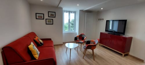 Salon moderne du Gîte Coquelicot au Mas de Trépeloup, Alès, avec canapé rouge, fauteuils rouges, télévision et vue sur les montagnes