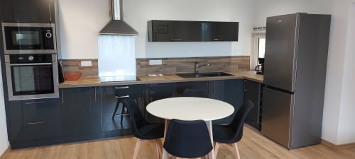 Cuisine moderne avec meubles sombres, plan de travail en bois et table ronde dans l'appartement Gîte Coquelicot à Alès, France