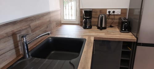 Kitchenette moderne du gîte Coquelicot avec évier noir, plan de travail en bois, cafetière et électroménager