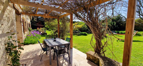 Espace repas sous pergola ombragée aux Granges Indigo avec table, chaises et vue sur le jardin luxuriant à Fossemagne
