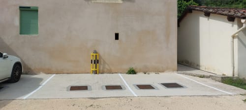 Parking privé du gîte Le Mas de Trépeloup près d'Alès, avec emplacements délimités et borne jaune.