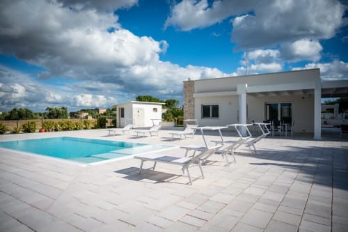 Modern villa in Ferrara with pool, lounge chairs, and patio overlooking countryside