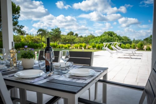 Terrazza elegante per cena all'aperto dell'hotel L.H.A. a Ferrara con vista sui vigneti, tavolo preparato con calici di vino e sedie lounge