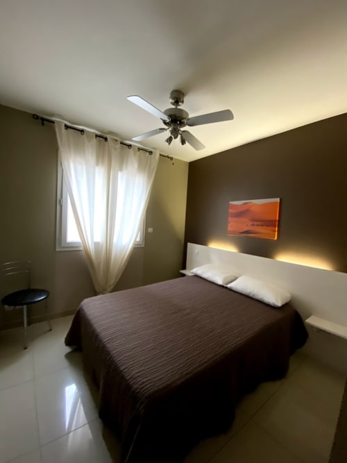 Chambre 1 lit en 140, placard à portes coulissantes-Meuble d'appoint-tête de lit éclairage à l'arrière-Ventilateur au plafond-climatisation