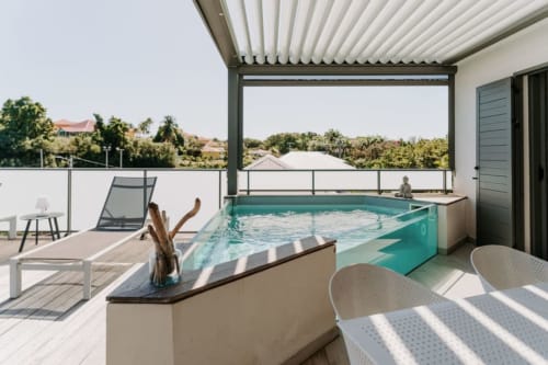 Terrasse piscine privée luxe à Habitation I'SEO, Sainte-Anne avec piscine turquoise, chaises longues et vue sur jardin