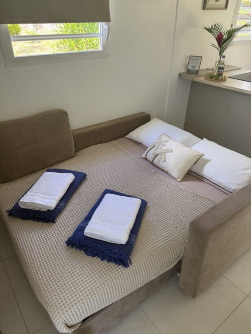 Chambre Ixora Bungalow au Domaine de la Glacière avec lits préparés, oreillers blancs et serviettes bleues à Petit-Bourg