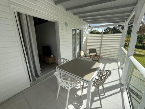 Patio du bungalow Balisier au Domaine de la Glacière, Petit-Bourg, avec table à manger, chaises blanches et terrasse couverte