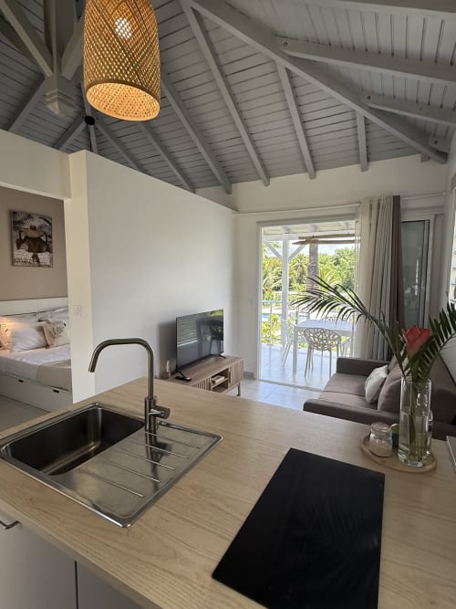 Kitchenette et séjour de la case Hibiscus au Domaine de la Glacière, vue piscine, aménagement ouvert