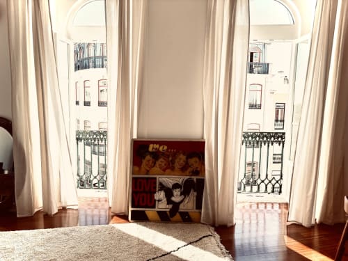 Bright Lisbon apartment with two arched windows, cream curtains, and wooden floors overlooking the city