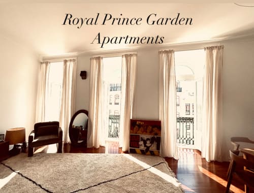 Bright living room in Royal Prince Garden Apartments, Lisboa, with large windows, cream curtains, wooden furniture, and city