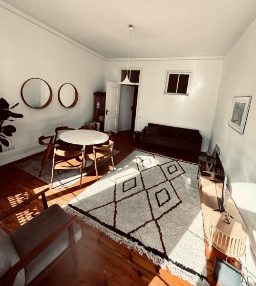 Modern living room at Royal Prince Garden Apartments in Lisbon with dining table, chairs, sofa, geometric rug, and round