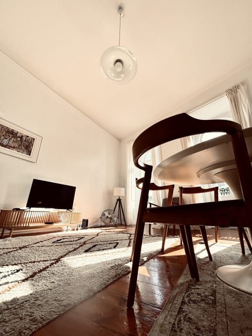 Modern apartment living room at Royal Prince Garden Apartments in Lisbon with dining table, TV, natural light, and city views