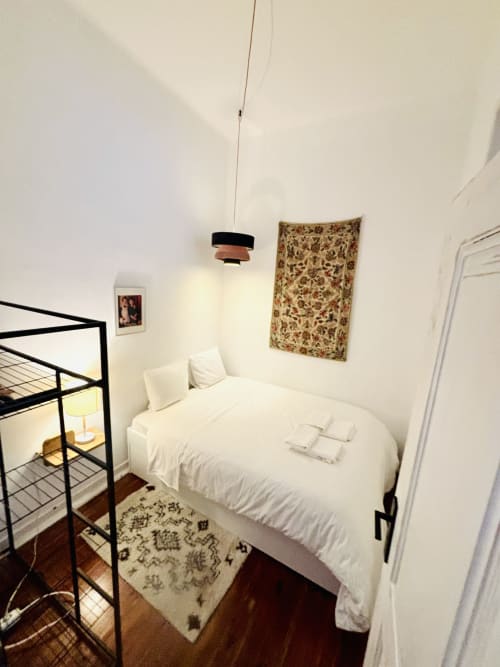Cozy bedroom at Royal Prince Garden Apartments in Lisbon with white bed, bunk bed, pendant light, and decorative tapestry