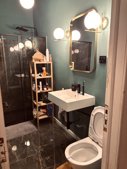 Modern bathroom in Royal Prince Garden Apartments Lisbon with dual vanity mirrors, black marble flooring, white sink, toilet,